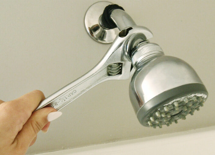 Woman's Hand Removing a Showerhead with a Shifter